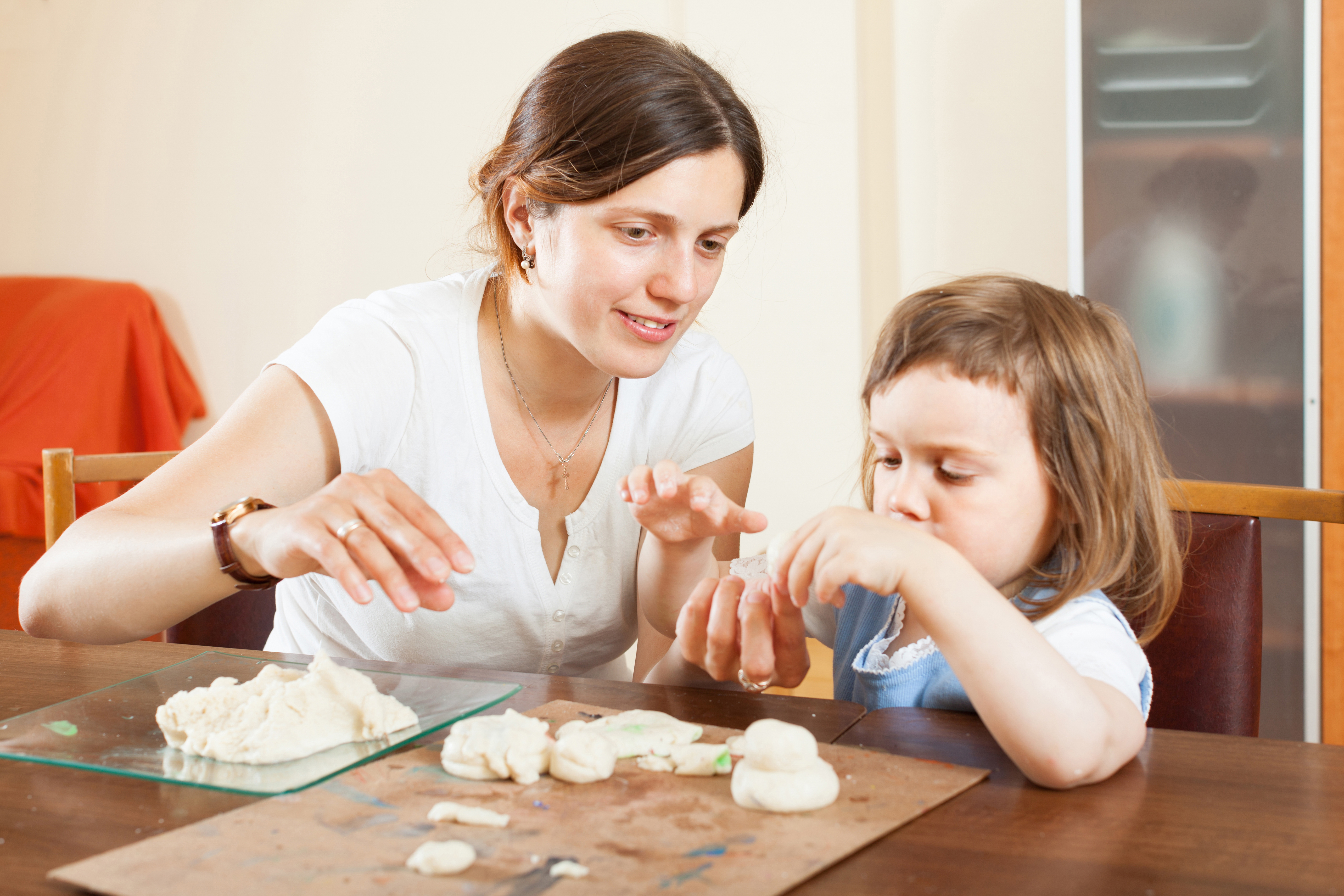 Happy mother and baby sculpting from plasticine or dough in home interior