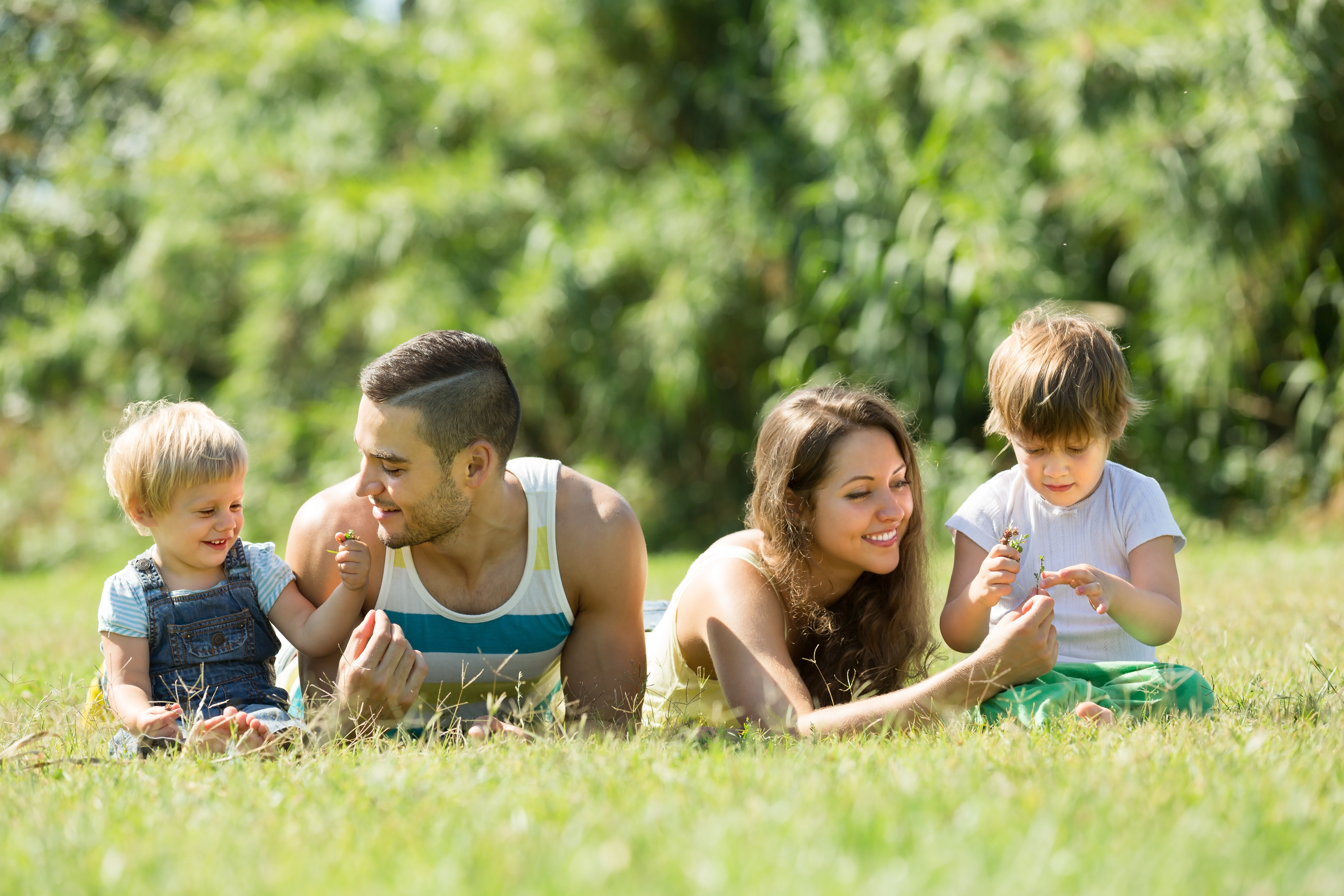 Happy family with little daughters laying in summer grass 